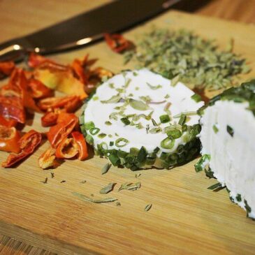 Roll of herb cheese on chopping board