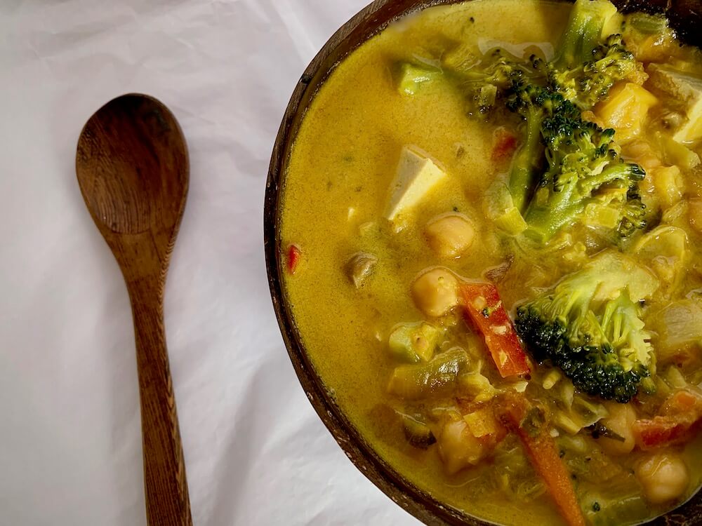Wooden spoon and bowl of vegan coconut curry