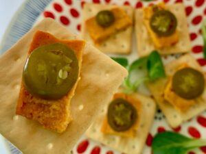 Slice of cashew cheese with jalapeño on gluten free cracker