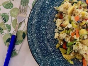 Half a blue plate with vegetable rice on it