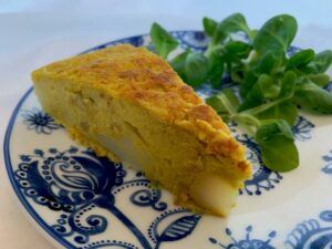 Slice of vegan omelette on a plate with lambs leaves
