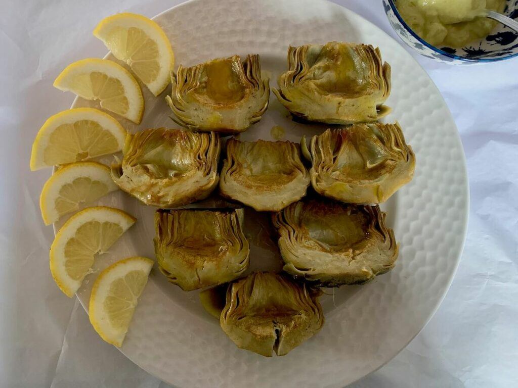 Plate of cooked artichokes with lemon slices