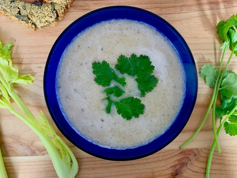 Blue bowl of celery soup with garnish of coriander leaves