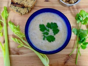 Blue bowl of celery soup with garnish of coriander leaves