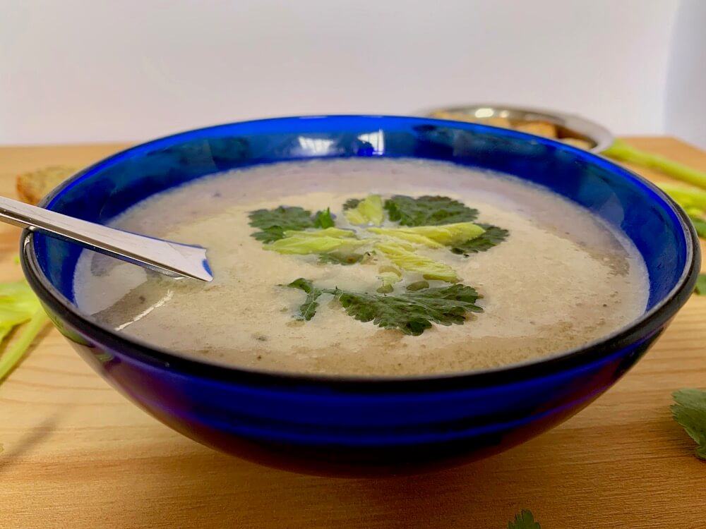 Blue bowl of celery soup with garnish of coriander leaves