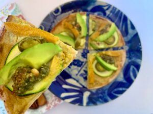 Slice of gluten free vegan pizza with avocado on top