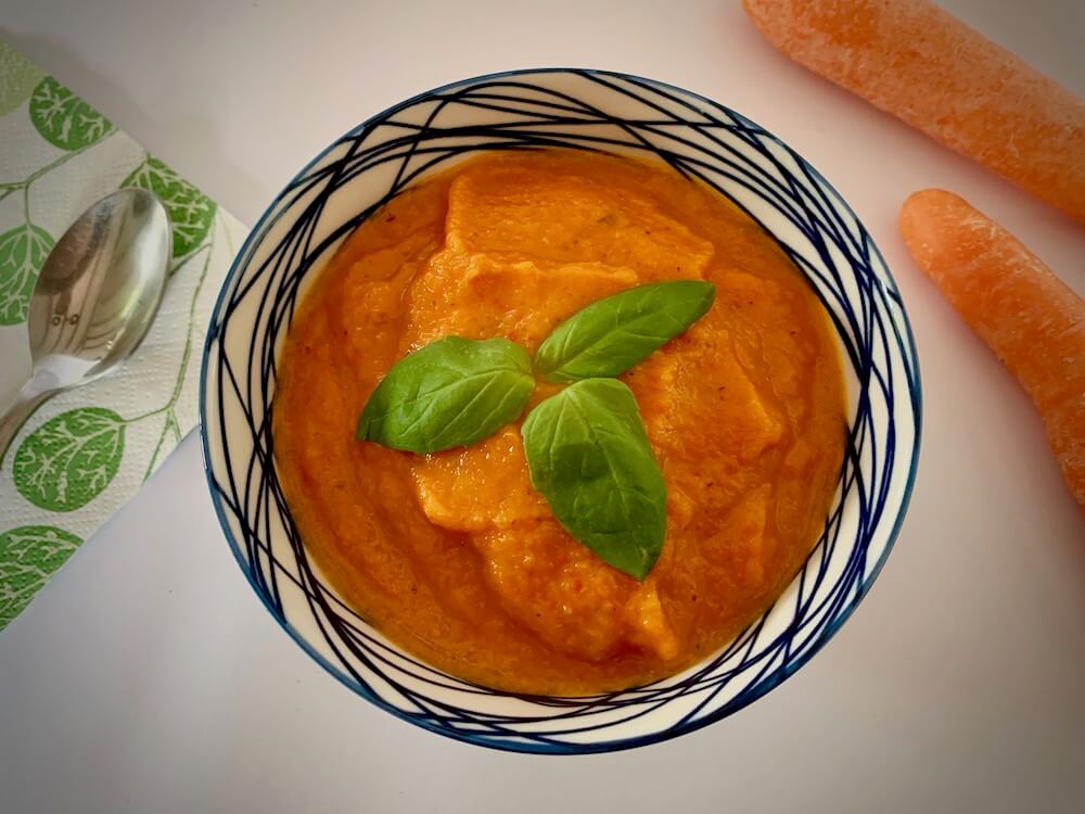Bowl of vegan carrot sauce with fresh basil on top