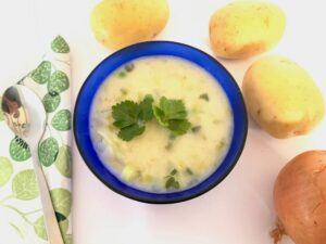 Blue bowl with quick potato soup and potatoes in the background