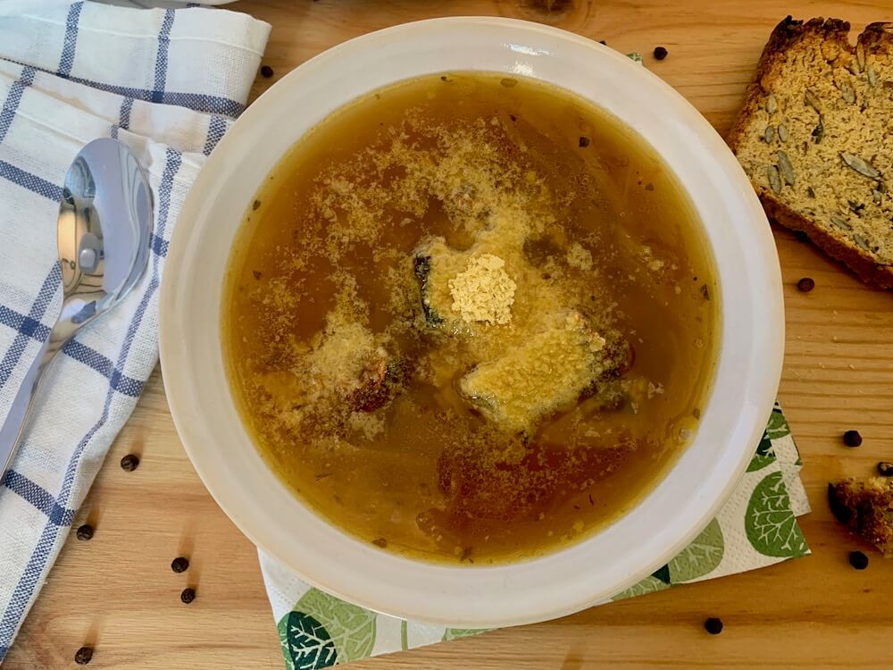 Bowl of vegan french onion soup with nutritional yeast on top