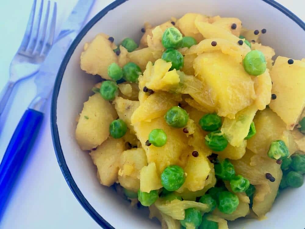 Potatoes and peas cooked in turmeric and black mustard seeds