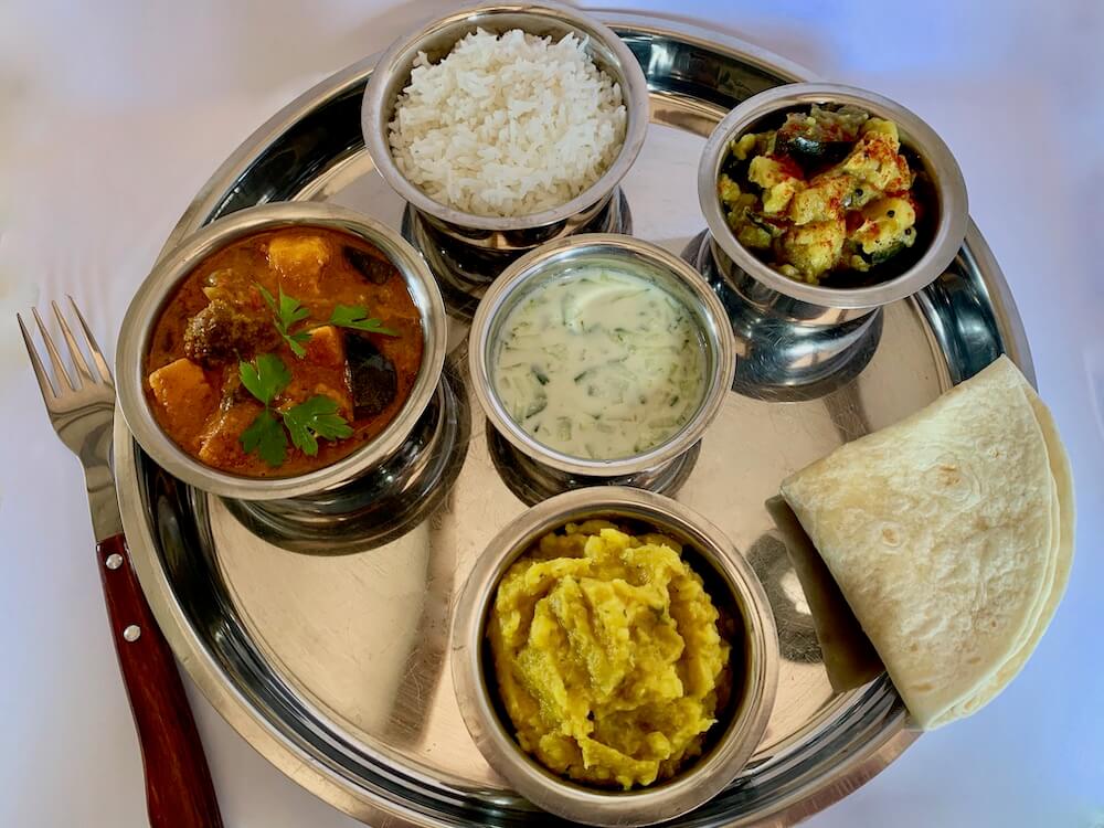 Vegan thali platter with rice, turmeric potatoes, dahl, sweet potato curry and gluten free flatbread