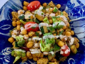 Bowl of quick chickpea recipe with broccoli & zucchini drizzled with tahini sauce