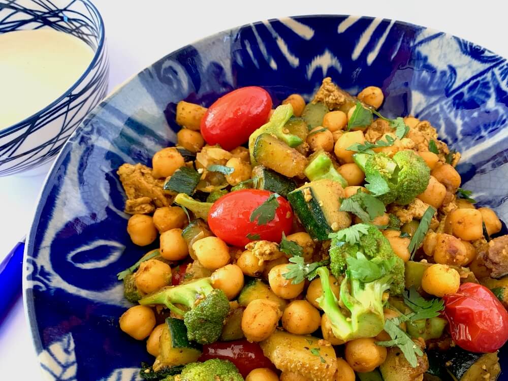 Bowl of quick chickpea recipe with broccoli & zucchini served with tahini sauce