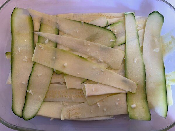 Thinly sliced zucchini in a casserole with garlic on top