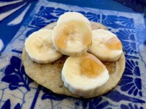 Gluten free vegan pancake with sliced banana and maple syrup on top