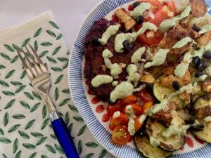 Bean burger with grilled veggies, drizzled with basil sauce