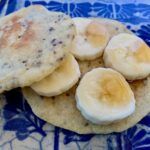 Vegan gluten free pancake with banana and maple syrup on top