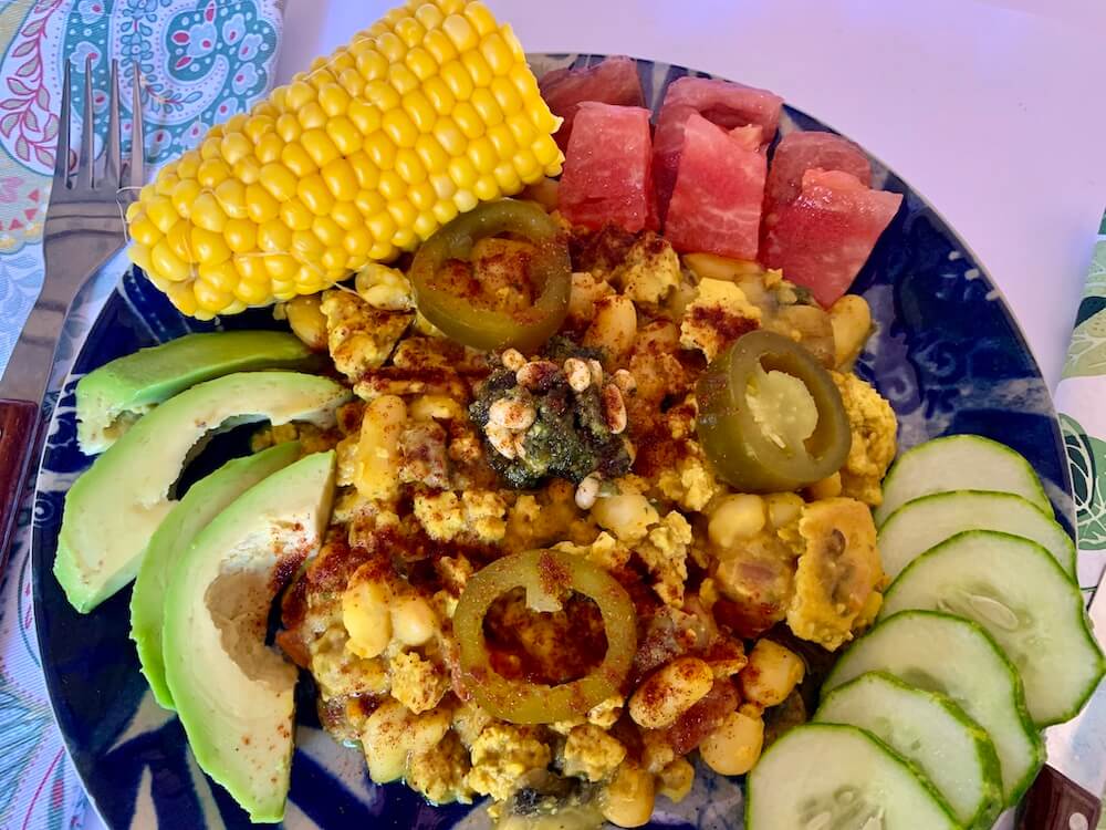 Blue plate with tofu scramble, avocado slices, tomato & cucumber