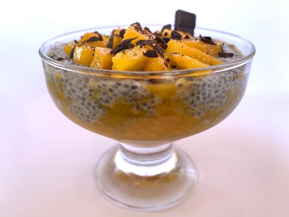 Bowl of chia seed pudding, with mango slices and dark chocolate