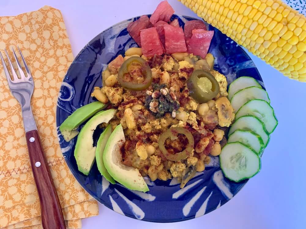 Blue plate with tofu scramble, avocado slices, tomato & cucumber