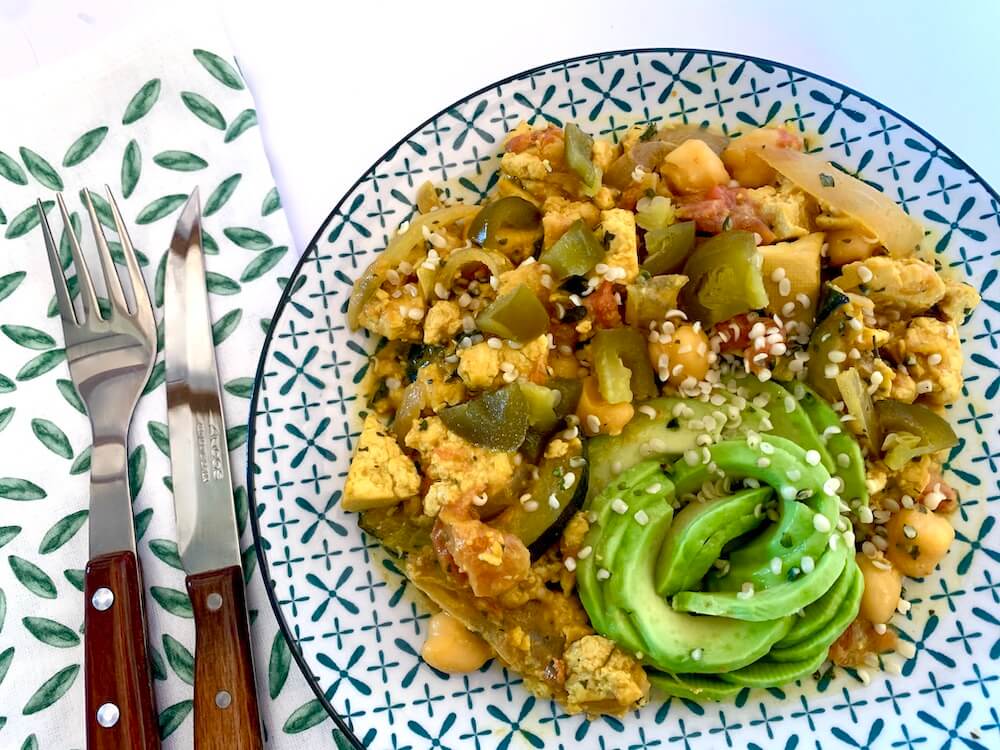 Plate of tofu scramble with an avocado rose on the side