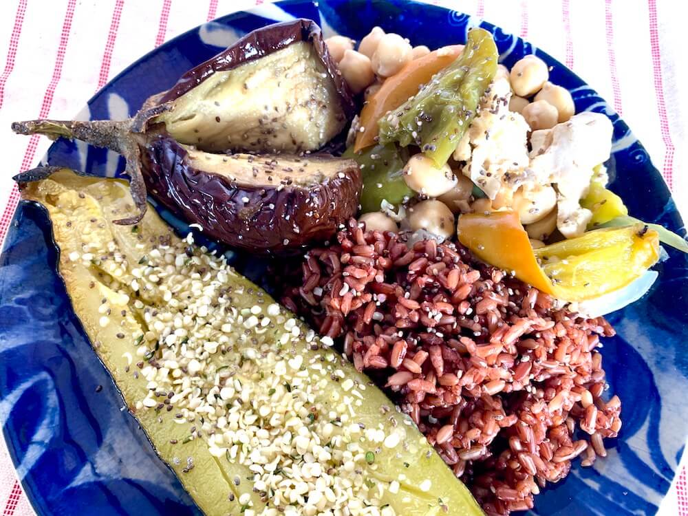 Roasted zucchini on a plate with red rice, roasted eggplant and chickpea bake