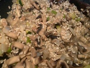 Raw rice added to the pan of mushrooms and onions