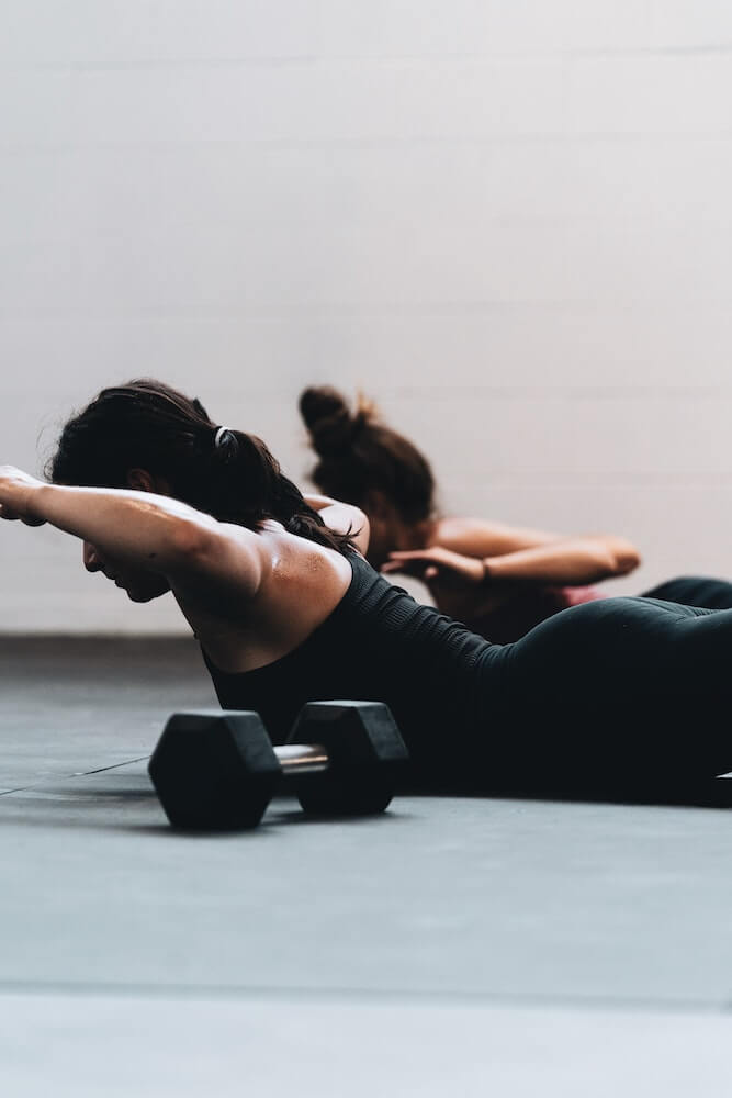 Woman doing exercise on floor with dumbbell beside her