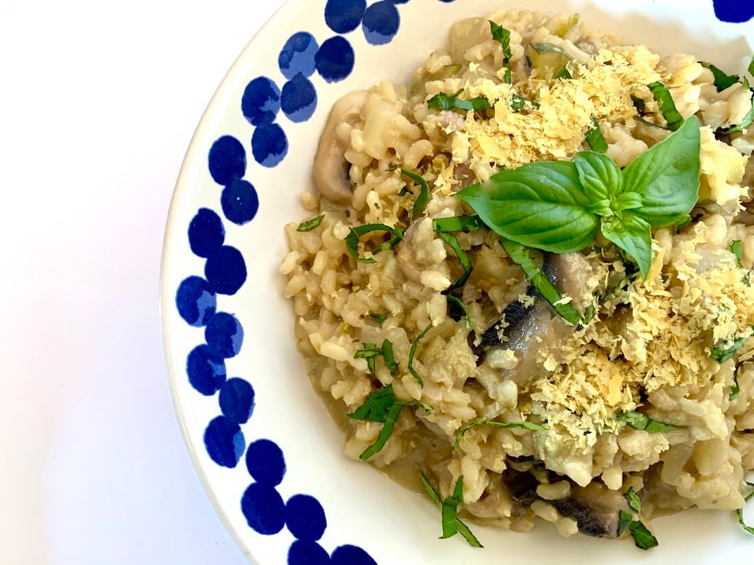 Blue and white bowl with vegan mushroom risotto topped with nutritional yeast