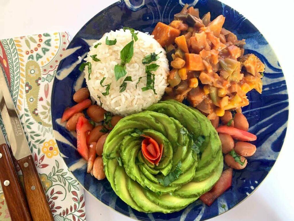 Plate of veggies with rice and an avocado rose 