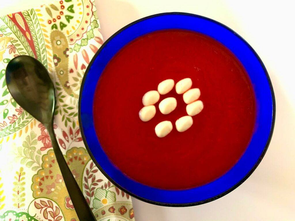Simple beetroot soup recipe served in a blue bowl with vegan cream on top 