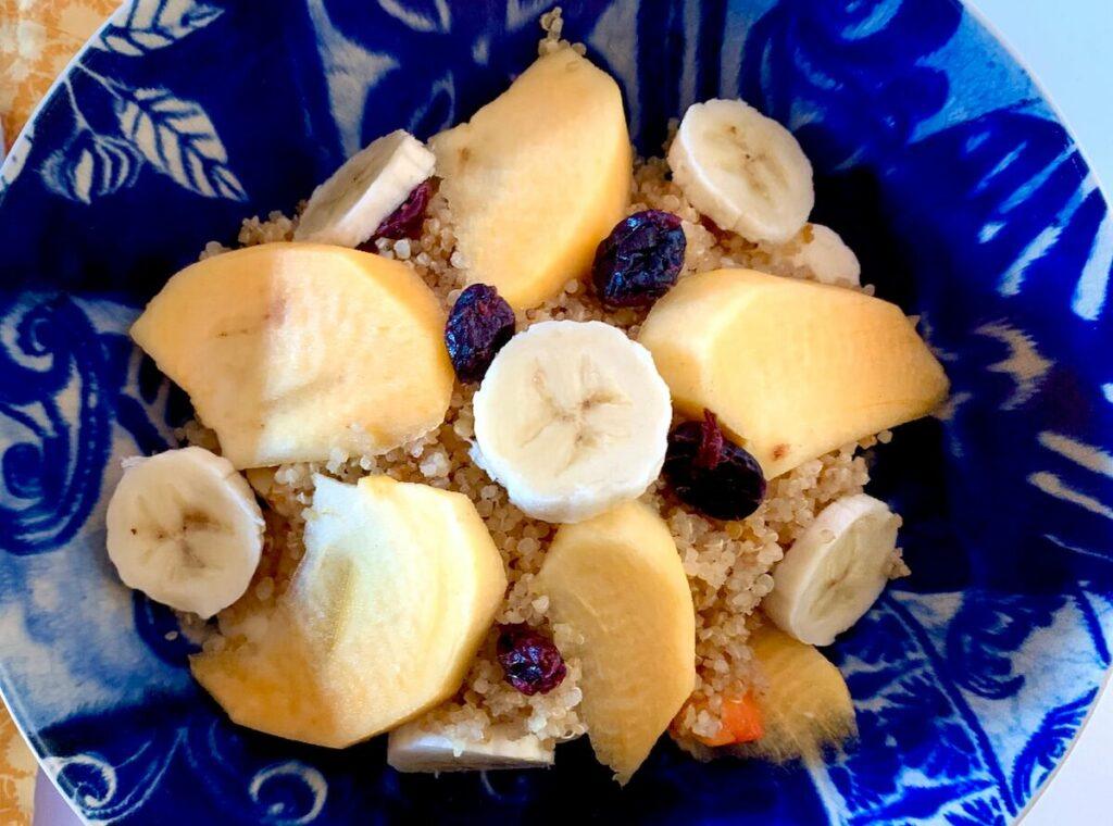 Bowl of quinoa with persimmon, banana and dried cranberries