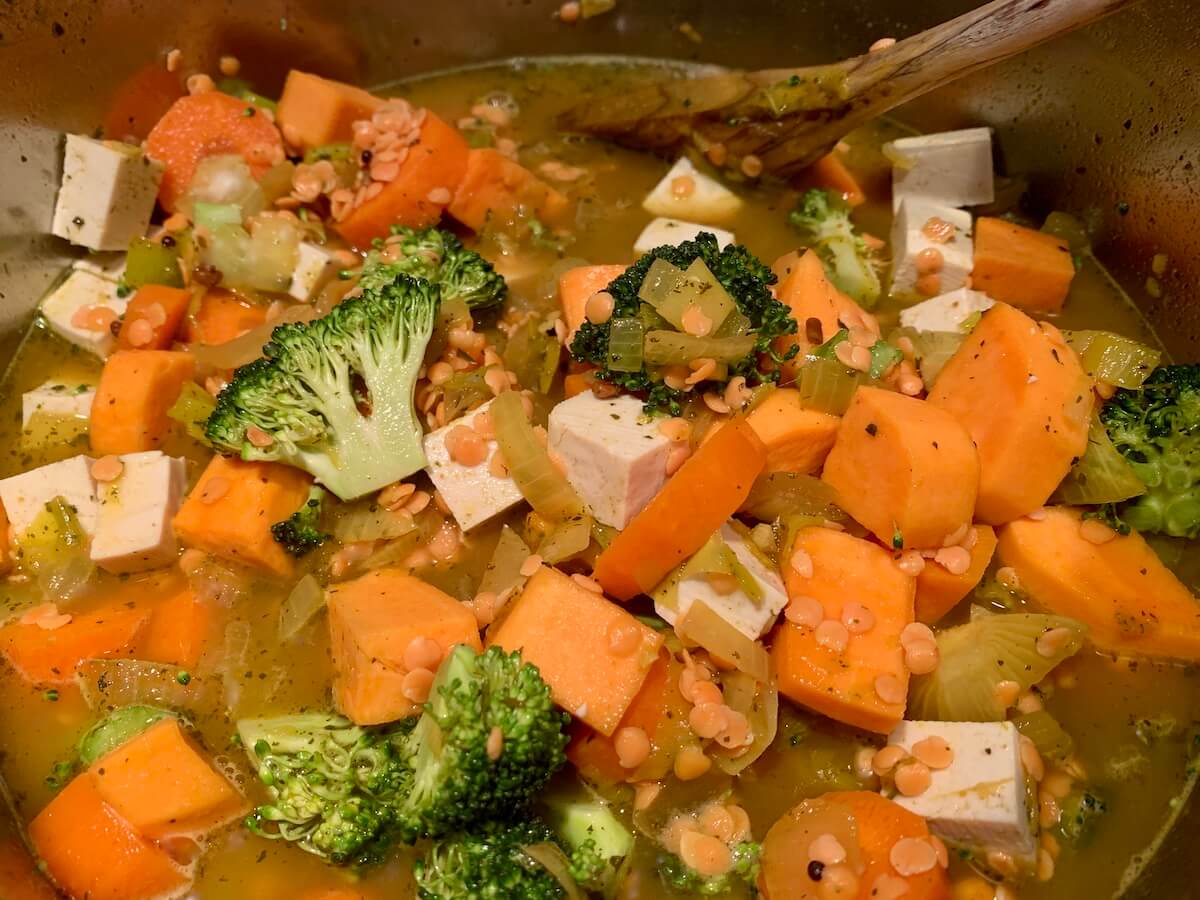 Sweet potato, carrot, broccoli, lentils and tofu in a pan with water and spices