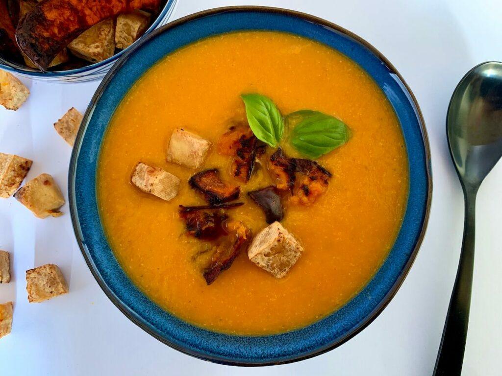 Bowl of roasted pumpkin soup with tofu croutons and pumpkin chips on top