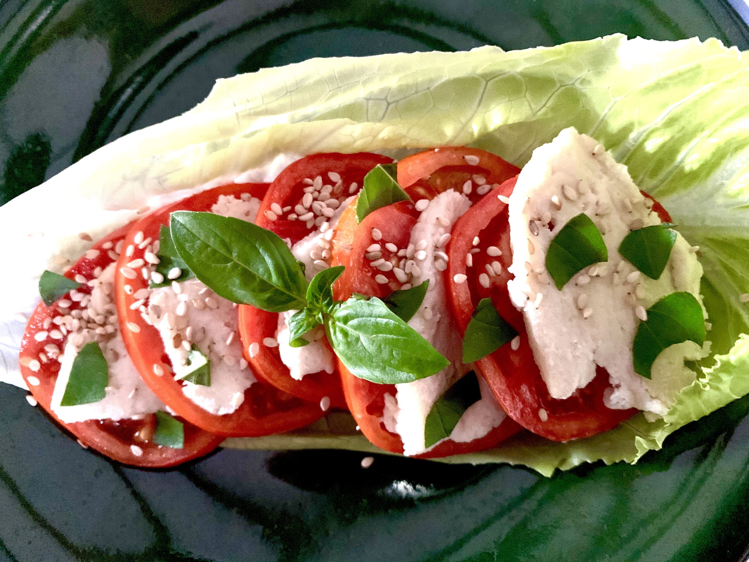 Vegan mozzarella and tomato salad in a lettuce leaf