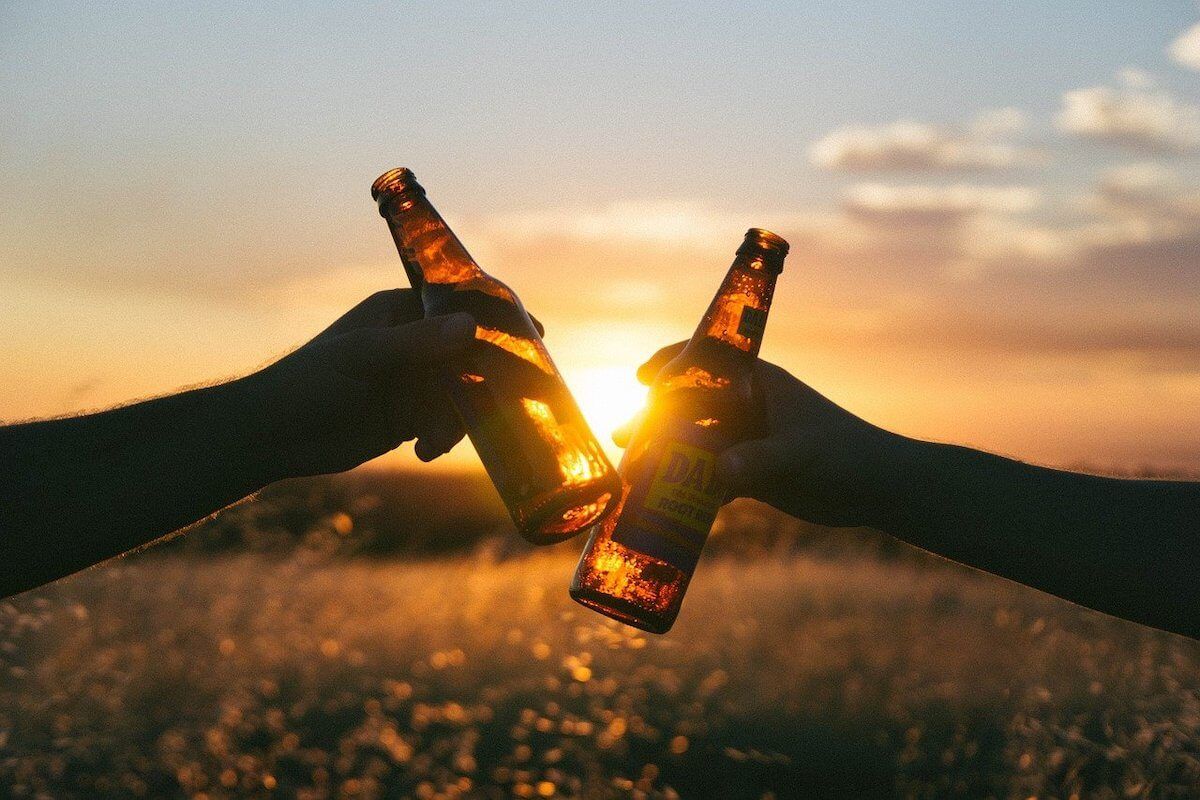 Two bottles raised against the sunset in a cheers movement