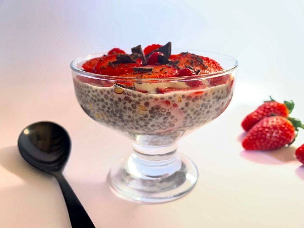 Strawberry chia seed pudding in a bowl with strawberries in the background
