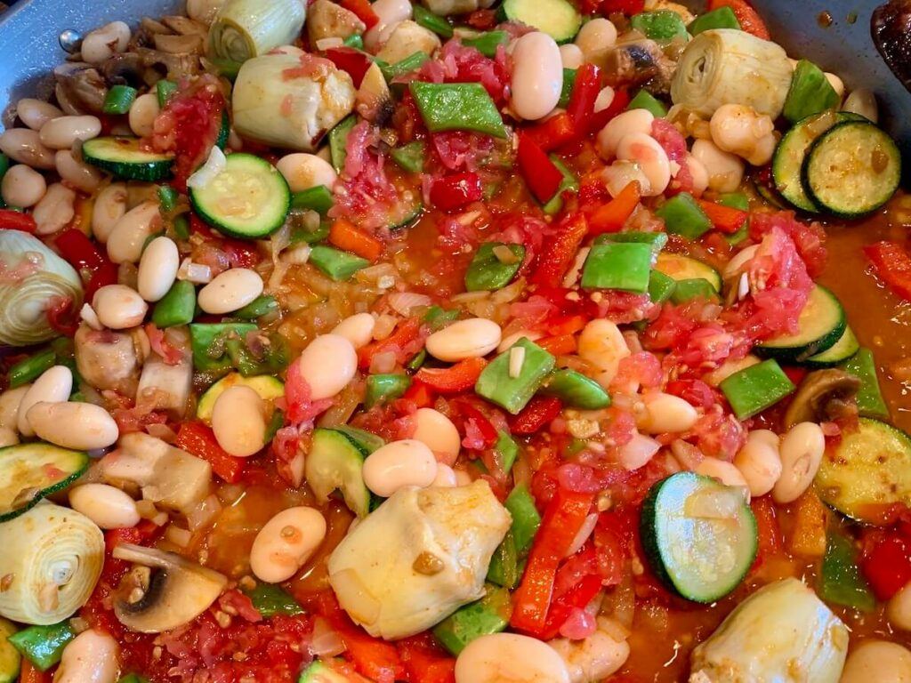 Vegetables and beans in tomato, cooking in a paella pan