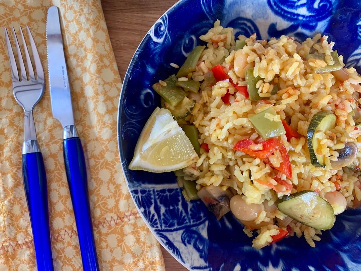 Bowl with vegetable paella and a slice of lemon