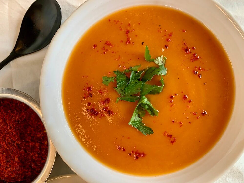 Bowl of roasted sweet potato & carrot soup sprinkled with chilli flakes
