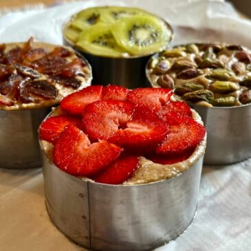 Raw vegan gluten free no bake cheesecake desserts with toppings of strawberry, date, kiwi and pistachios