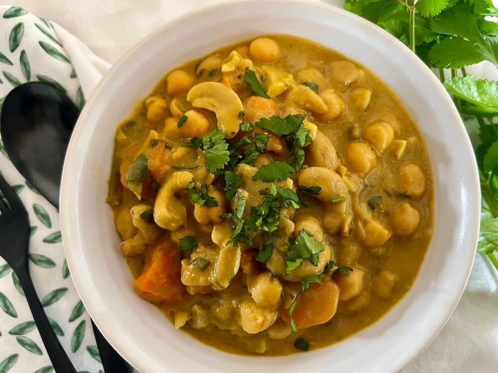 Bowl of sweet potato with chickpeas and cashews in a coconut sauce, served as a stew