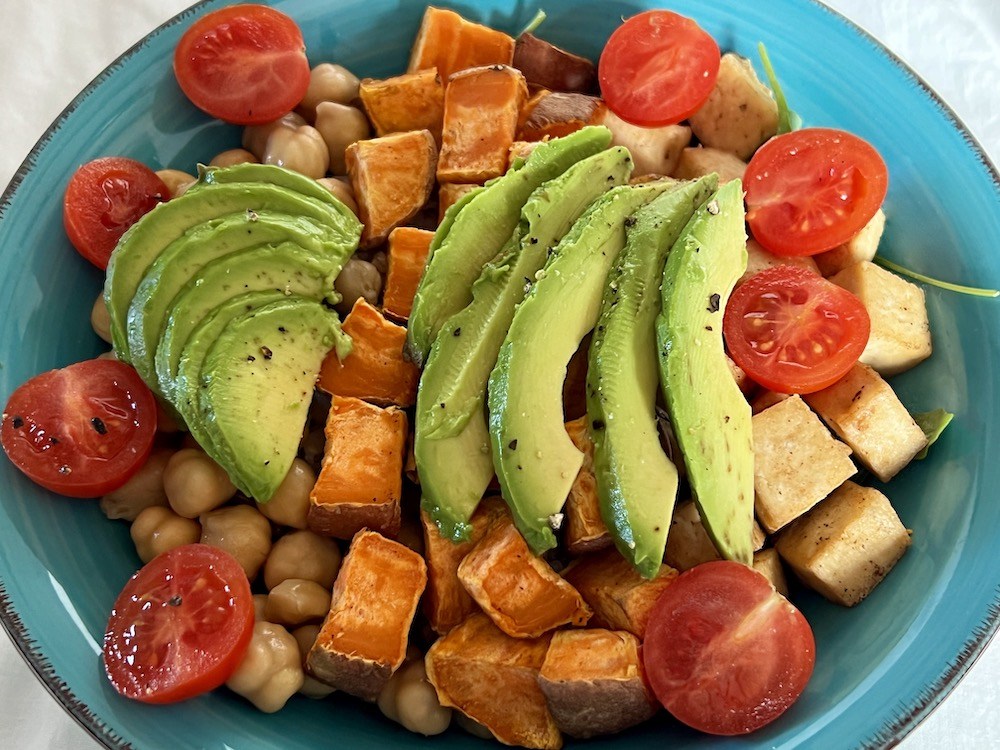 vegan bowl topped with avocado, cherry tomatoes and black pepper