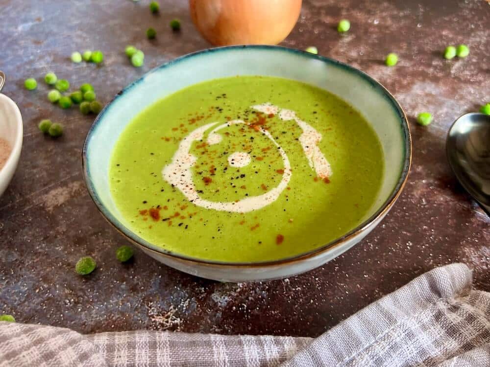 Bowl of easy vegan pea soup with chilli and cream on top