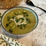A bowl of broccoli soup with parsley and vegan cream on top,demonstrating how to fix bland broccoli soup