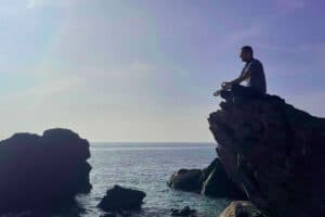 Person sitting on a rock meditating