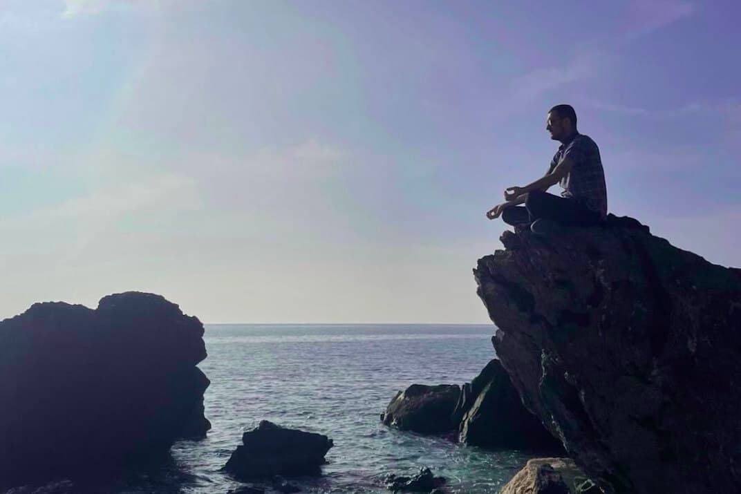 Person sitting on a rock meditating