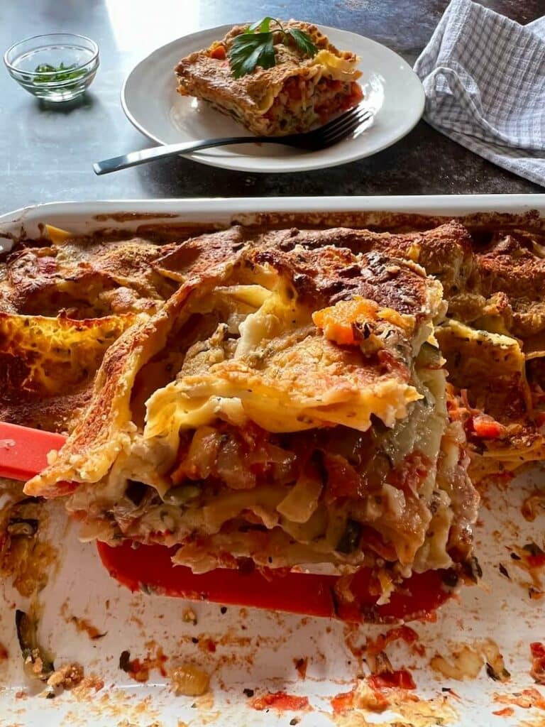 how to make easy oil free vegan lasagne - slice of lasagne in foreground with serving in background