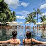 Can I meditate while travelling? Two women sitting in a tropical pool with their backs to the camera.