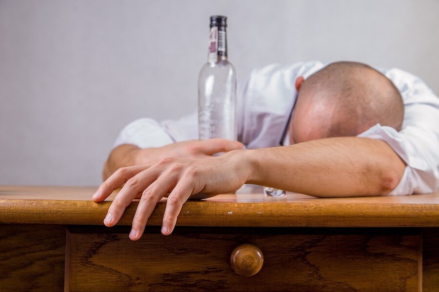 Can I fast with a hangover - man lying with his head on the table and an empty bottle in his hands